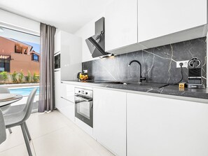 Una cocina moderna con encimera de mármol negro, horno empotrado y grifo negro.