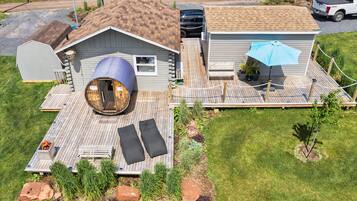 Una casa con una amplia terraza de madera, una estructura circular de madera y un área de estar al aire libre techada.