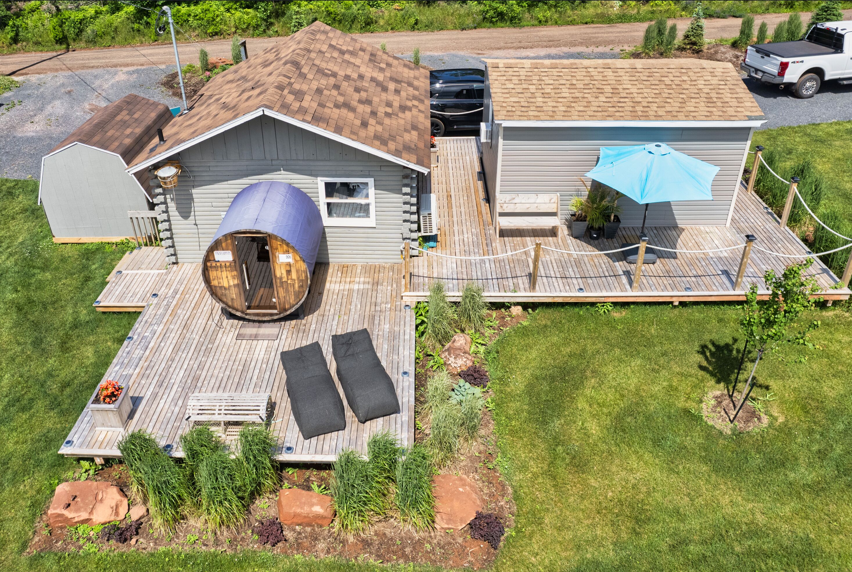 A house with a large wooden deck, a circular wooden structure, and a covered outdoor seating area.