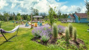 En baghave med hængekøje, havemøbler, en pergola og et hus.