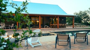 Una casa moderna con un porche cubierto, mobiliario exterior y una piscina.