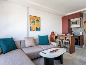 A modern living room with a sofa, a coffee table, and a kitchen area with a microwave. - Charmante Wohnung 42 by Interhome (Casablanca)