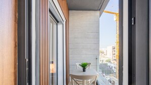 A narrow balcony with a table and chairs, a potted plant, and a view of the cityscape and construction cranes. - Charmante Wohnung 42 by Interhome (Casablanca)