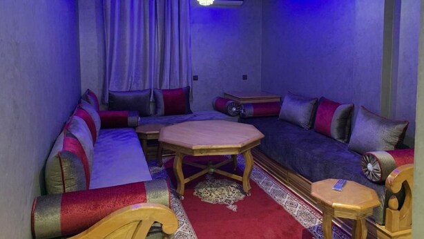 Ein Zimmer mit einer Eckcouch, einem kleinen Holztisch und einer Kristallleuchtre.