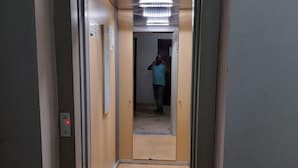 A narrow hallway with a carpeted floor, a door at the end, and a person in a blue shirt standing in the distance. - Résidence Annasr 1 by Interhome (Agadir)