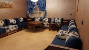 A living room with a sofa set, a wooden coffee table, and a dining table. - Résidence Annasr 1 by Interhome (Agadir)