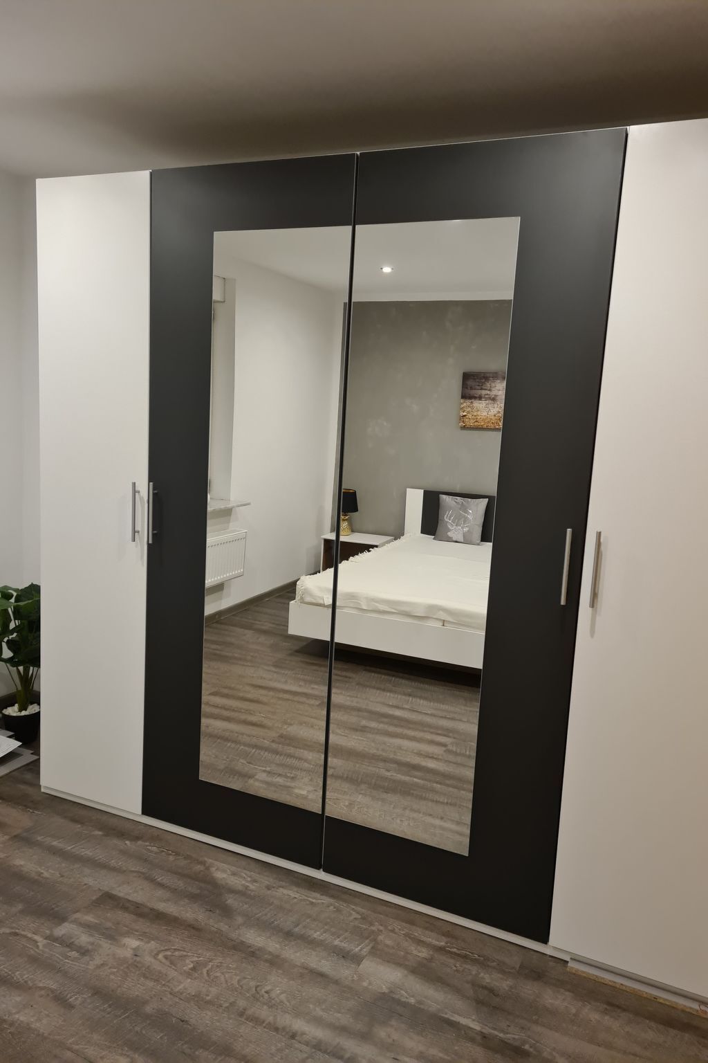 Ein Schlafzimmer mit großem Kleiderschrank, einem Bett und einem Nachttisch.