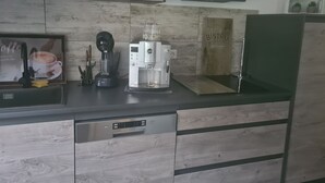 Eine moderne Küche mit einer Kaffeemaschine, einem Geschirrspüler und einem grünen Kühlschrank.
