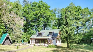 Une maison à deux étages, dotée d’un toit végétalisé, entourée d’une pelouse verdoyante et d’arbres.