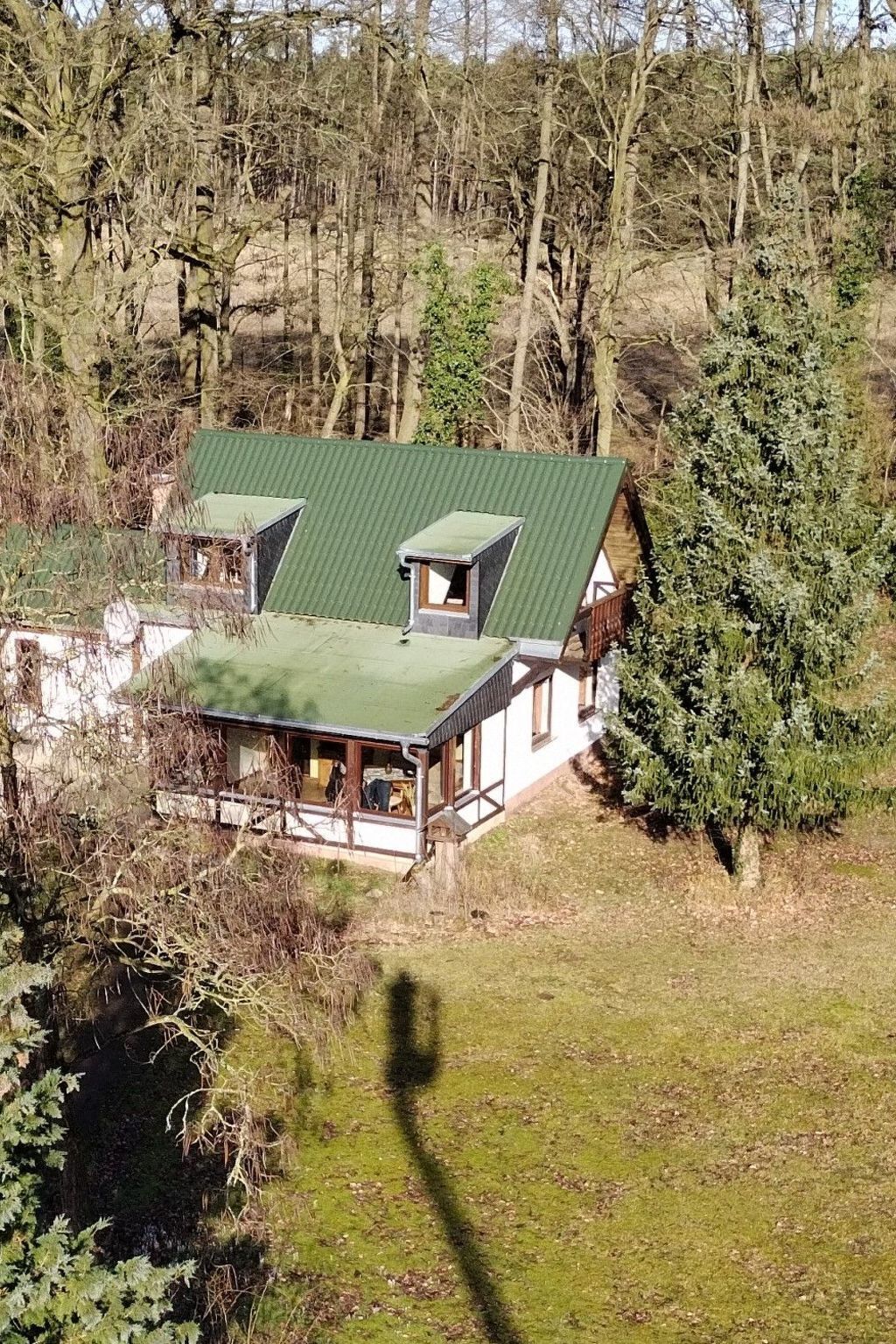 Ein Haus mit einem grünen Dach, einem kleinen Gaubenfenster und einer Veranda.