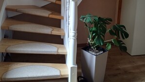 Un escalier avec des marches en bois et des balustrades blanches, une plante en pot et une poubelle.
