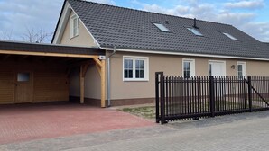 Una casa de dos pisos con techo inclinado, garaje y cerca de metal negro.