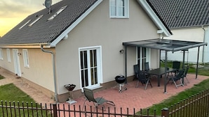 Una casa con porche techado, antena parabólica y parrilla.