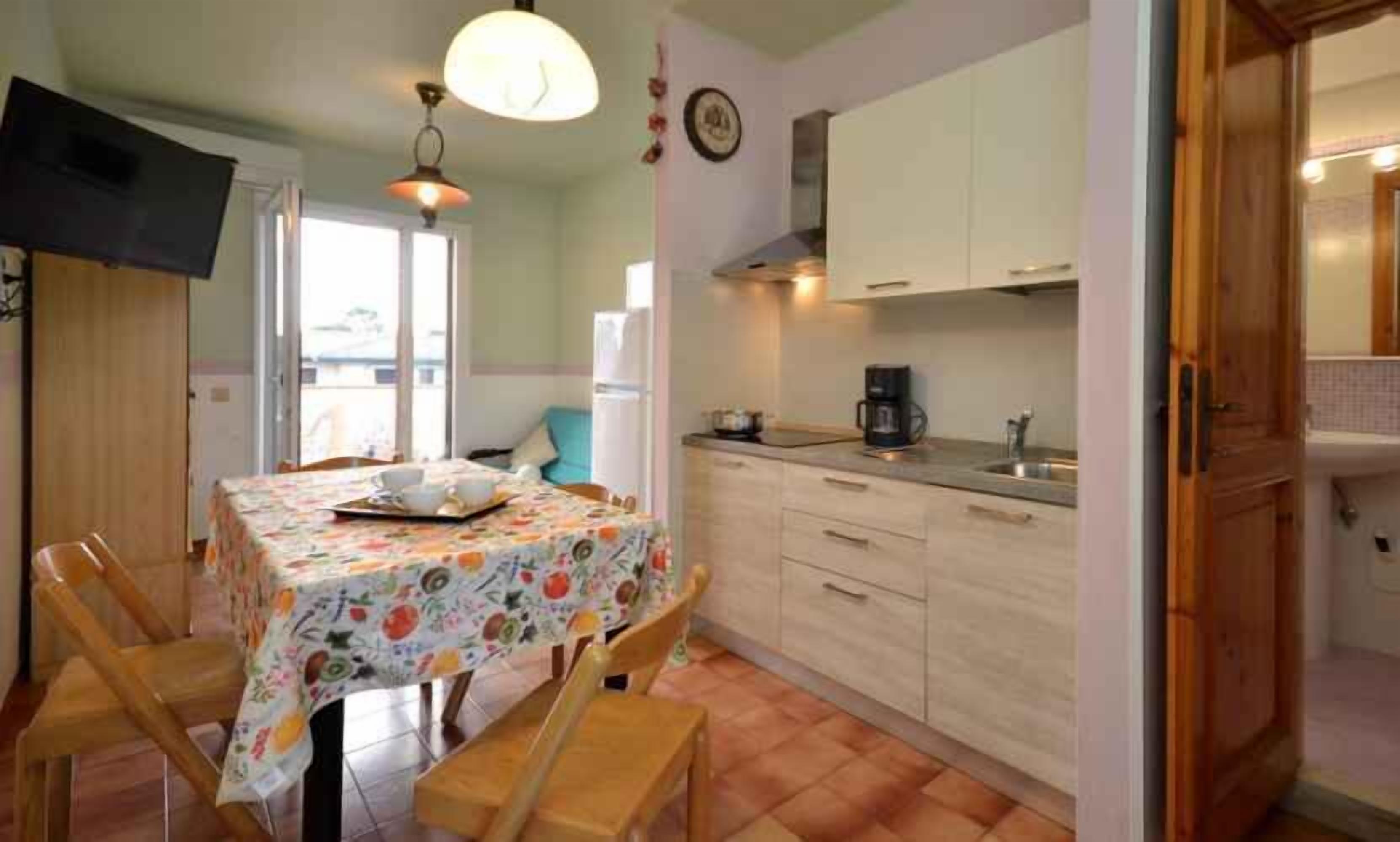 A small kitchen with a dining table, chairs, and a coffee maker.
