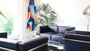 Una sala de estar moderna con un sofá de cuero negro, una mesa de centro de vidrio y un cuadro abstracto grande en la pared.