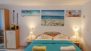 A bedroom with a bed, two bedside lamps, a nightstand, a wardrobe, and three wall-mounted paintings. - Rotkehlchen by Interhome (Bannesdorf)
