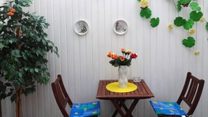A small room with a wooden table and chairs, a clock, and a vase with flowers. - Rotkehlchen by Interhome (Bannesdorf)