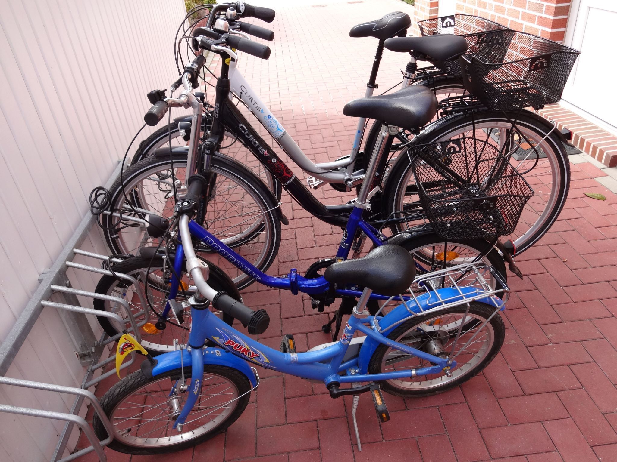 A blue bicycle with a basket and a black bicycle with a rear rack.