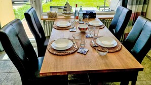 Mesa de comedor para seis personas, con platos, vasos y cubiertos, con vista a un lago.