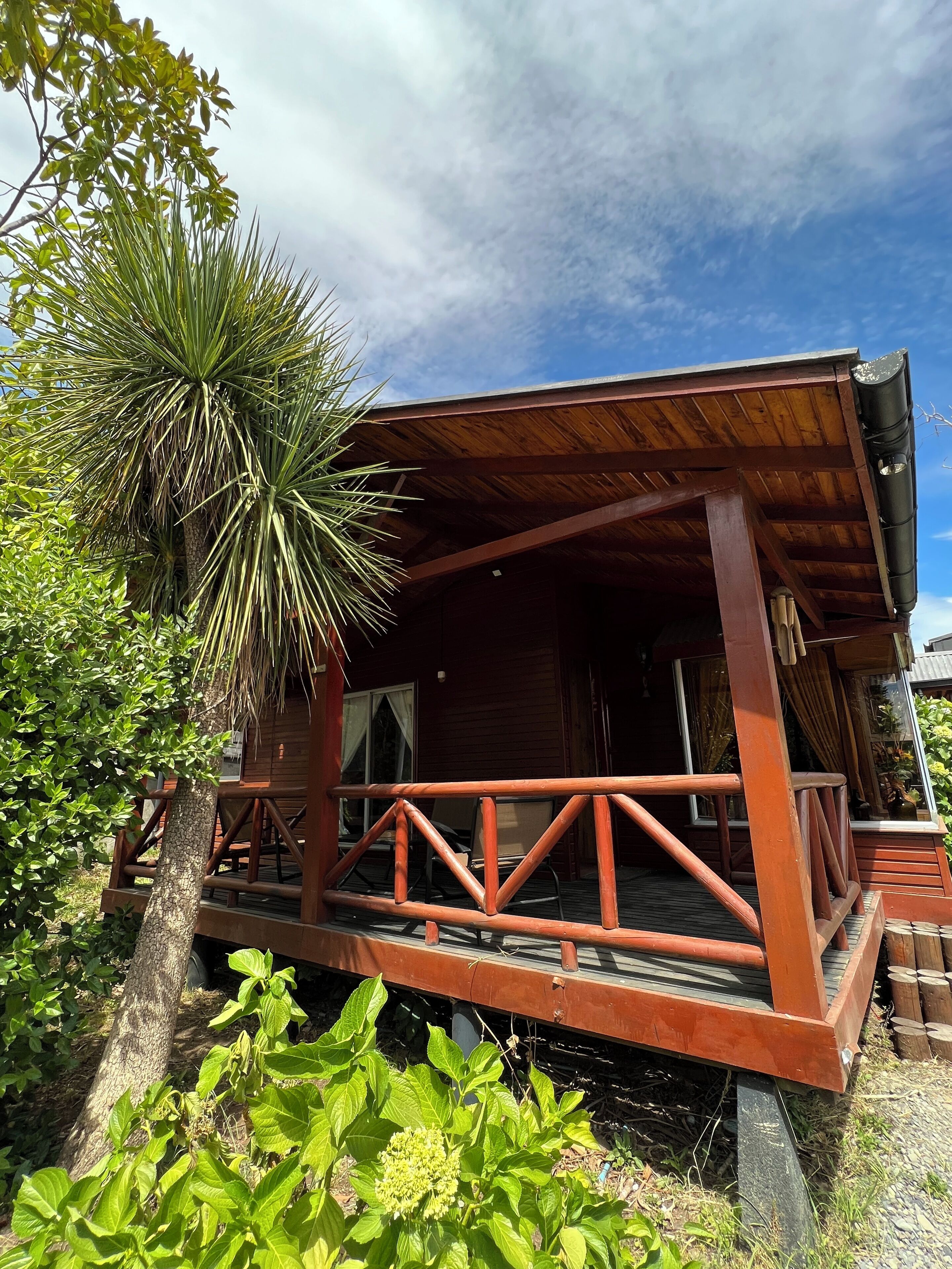 A wooden cabin with a porch, surrounded by greenery.