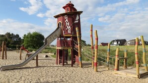 A playground with a slide and climbing structures on a sandy area. - Körner Kornhof 7 EG by Interhome (Dahme)