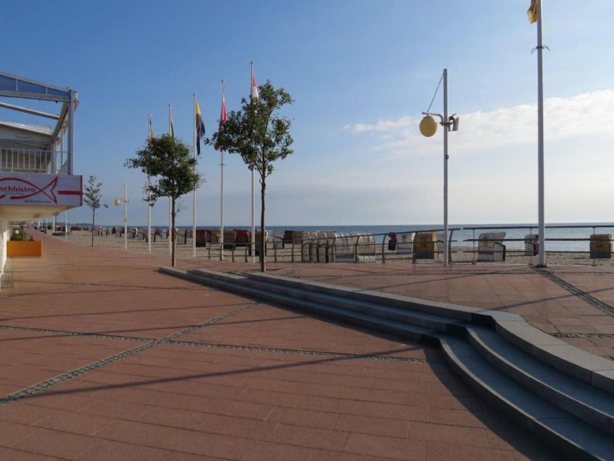 A seaside promenade with a restaurant named 'Schibistro' and a view of the sea.