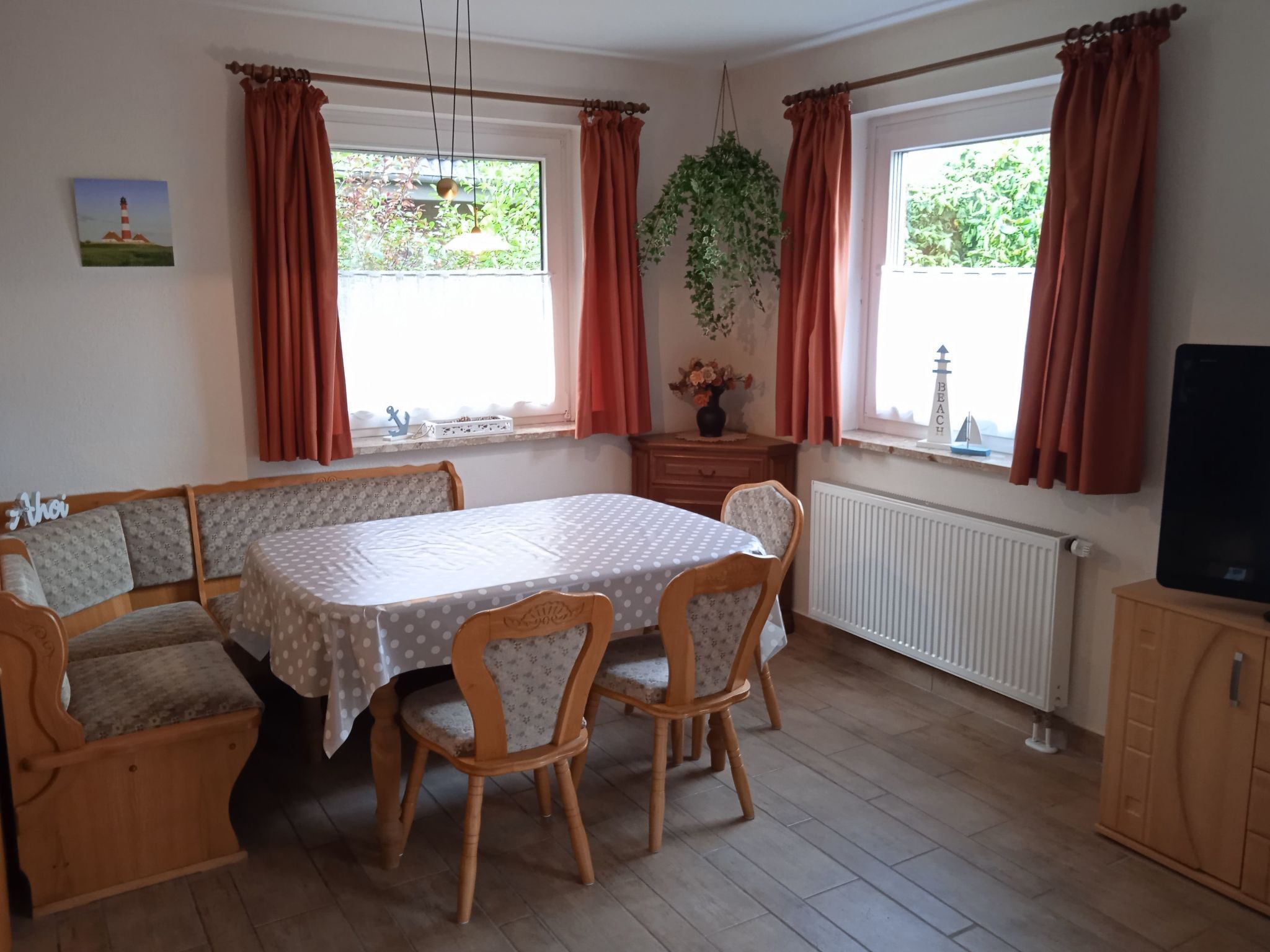 Een gezellig eetgedeelte met een tafel en stoelen, een bankje, een radiator en een televisietoestel op een kast.