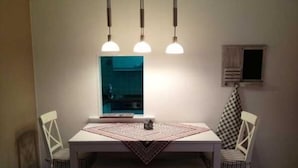 A dining area with a white table, three pendant lights, and two chairs. - Apartment Höller by Interhome (Grömitz)