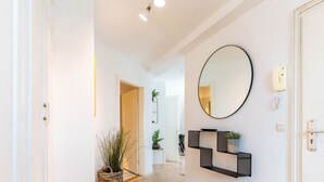 A hallway with a wooden floor, a round mirror on the wall, a wicker basket with plants, and a small shelf with decorative items. - Himmelskoje mit Große Dachterrasse & Hafenblick by Interhome (Altstadt)