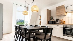 A modern kitchen with a dining area, featuring a large window, wooden cabinets, and a built-in oven. - Himmelskoje mit Große Dachterrasse & Hafenblick by Interhome (Altstadt)