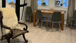 A dining area with a wooden table and four chairs, a fur-covered chair, and a window with curtains. - Zeppelinkoje by Interhome (Altstadt)