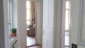 Un pasillo con suelo de madera que conduce a una habitación con cama y ventana.