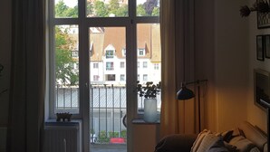 Una habitación con un ventanal grande, un sofá, una lámpara y una mesita baja con adornos.
