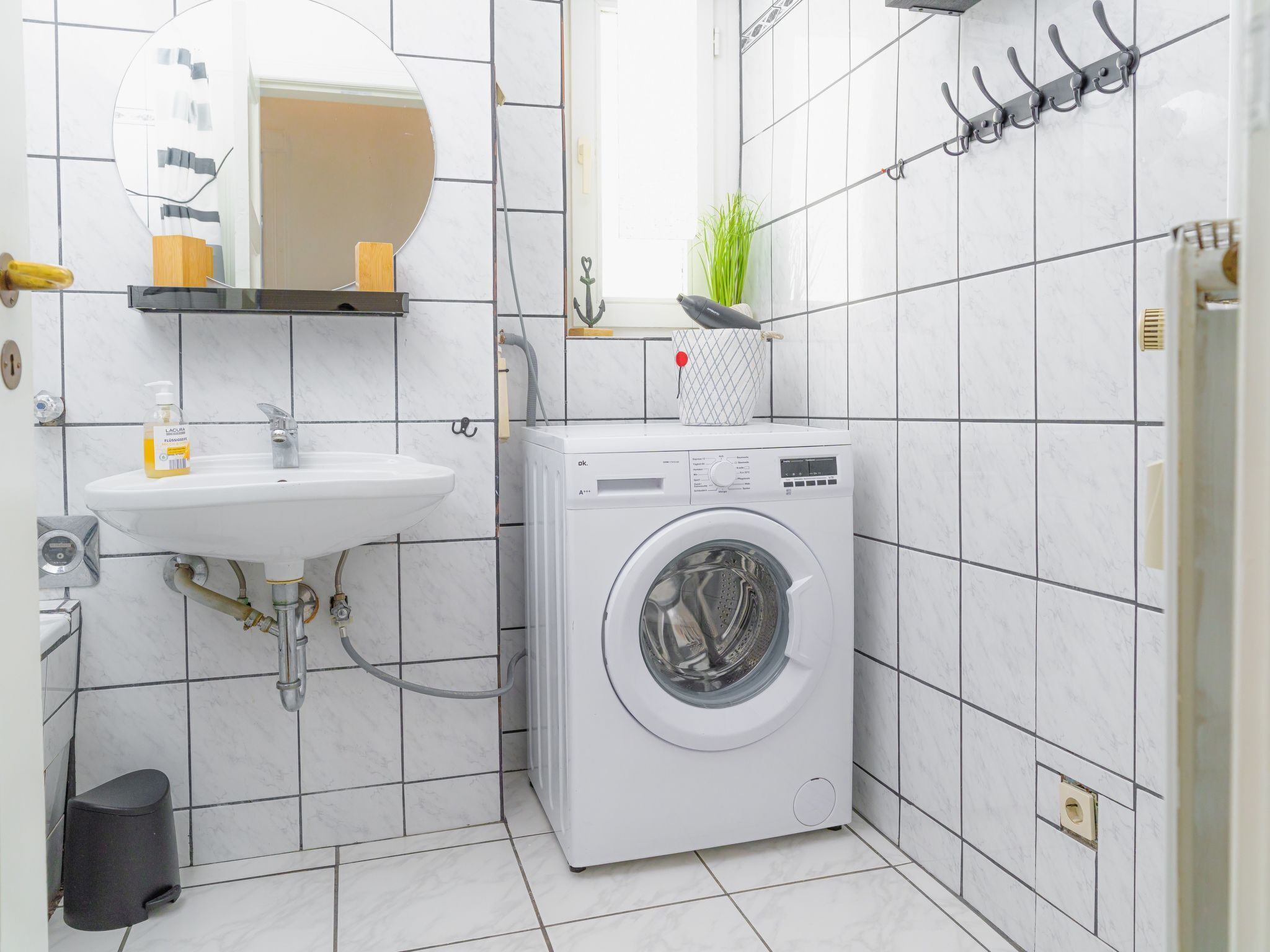 Un bagno piccolo con lavandino, specchio e lavatrice.