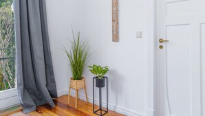 A room with a wooden floor, a white door, a grey curtain, and two potted plants. - Koje Marina by Interhome (Altstadt)