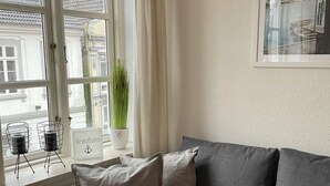 Un soggiorno moderno con un divano ad angolo grigio, una pianta in vaso e un quadro appeso al muro.
