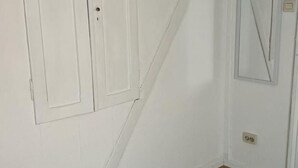 Una stanza con pareti bianche, pavimento in legno e due porte.