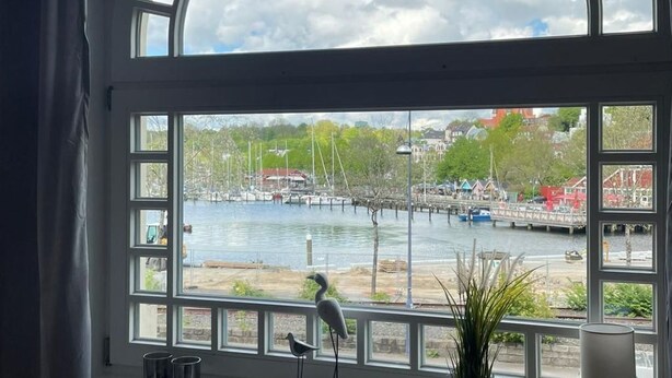 Ein Zimmer mit einem großen Bogenfenster mit Blick auf eine Marina, in der Boote und Gebäude liegen.