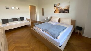 Ein modernes Schlafzimmer mit einem großen Bett, einer Schlafcouch und einem Bild an der Wand.