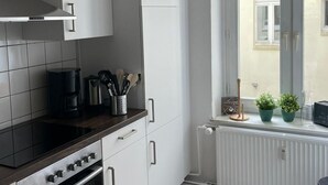 Eine moderne Küche mit weißen Schränken, einer schwarzen Arbeitsplatte und einem eingebauten Backofen. Ein Fenster bietet Blick auf ein Gebäude.