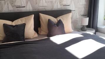 Une chambre à coucher avec un lit, des oreillers, une table de chevet et une lampe.
