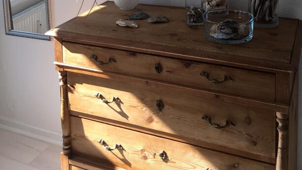A wooden dresser with drawers, a decorative anchor on the wall, a potted plant, and a glass vase with seashells. - Admiralskoje by Interhome (Altstadt)