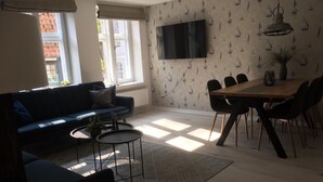 A modern living room with a sofa, coffee table, and dining area with chairs. - Admiralskoje by Interhome (Altstadt)