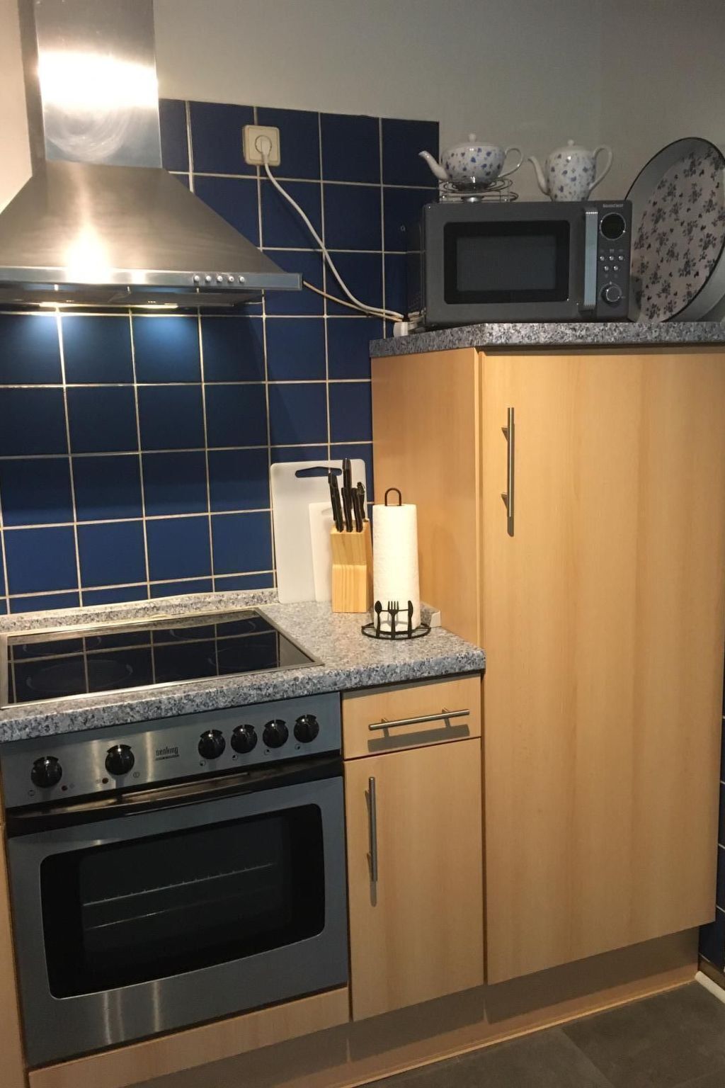 Une cuisine équipée d’une cuisinière, d’un four, d’un four à micro-ondes et de meubles de rangement en bois.