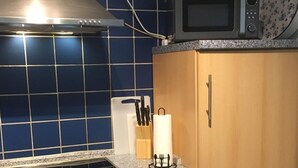 A kitchen with a stove, oven, microwave, and wooden cabinets. - Admiralskoje by Interhome (Altstadt)