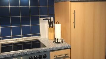 Une cuisine équipée d’une cuisinière, d’un four, d’un four à micro-ondes et de meubles de rangement en bois.