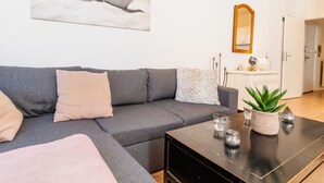 Ett modernt vardagsrum med en grå soffa, ett soffbord och en stor, abstrakt tavla på väggen.
