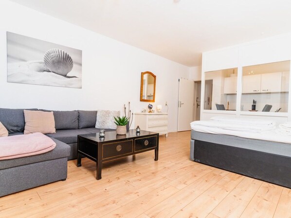 A modern living room with a grey sofa, a wooden coffee table, and a large bed. - Koje Sansibar by Interhome (Altstadt)
