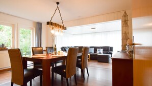 Una sala moderna con un sofá de cuero oscuro, una mesa de comedor de madera con sillas y una lámpara colgante.