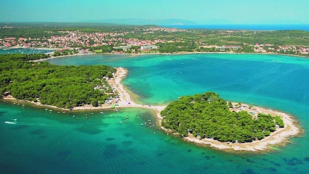 An aerial view of a coastal area with a small island surrounded by clear turquoise waters, a beach, and a densely vegetated area. - Modernes und komfortables Wohndesign by Interhome (Medulin)